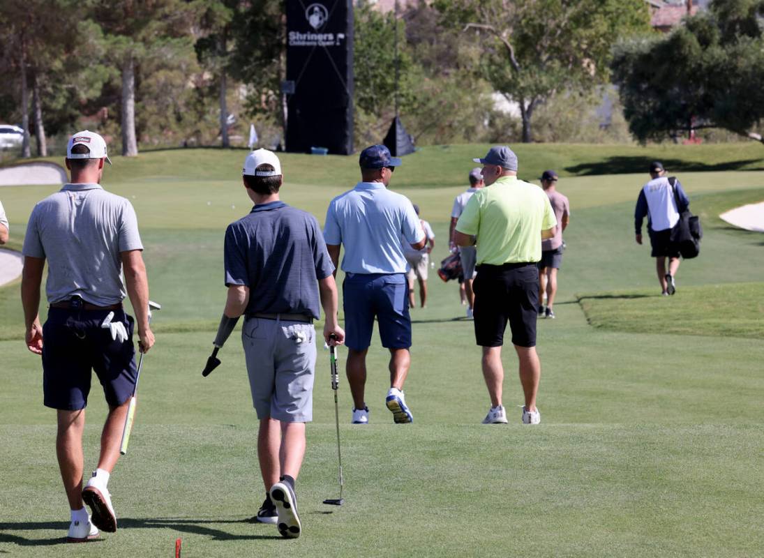 Shriners patient ambassador Isaac Berger, 17, of Neillsville, Wis., right, walks with PGA Tour ...