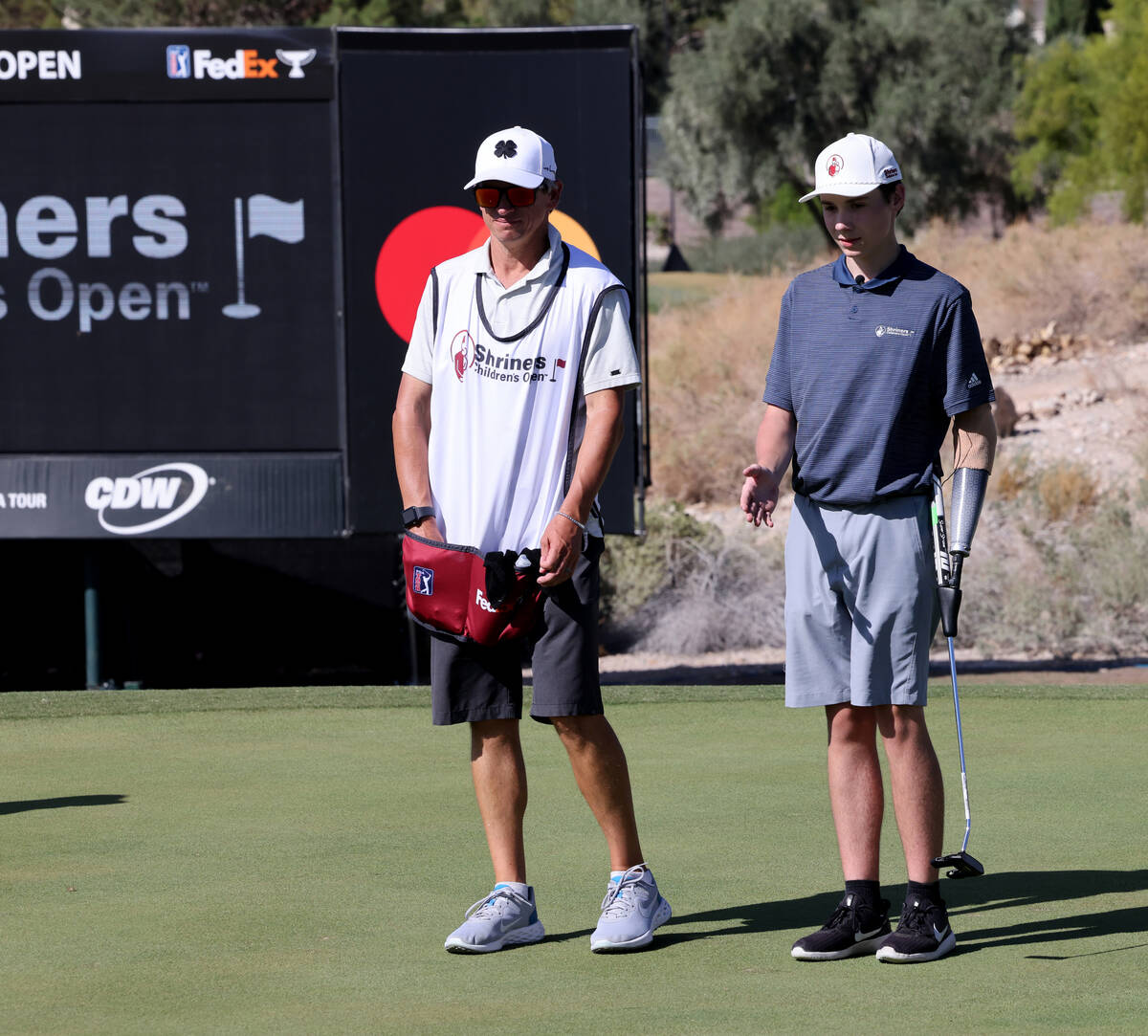 Shriners patient ambassador Isaac Berger, 17, of Neillsville, Wis., right, lines up his putt on ...