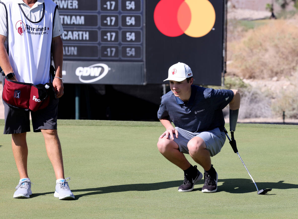 Shriners patient ambassador Isaac Berger, 17, of Neillsville, Wis., right, lines up his putt on ...