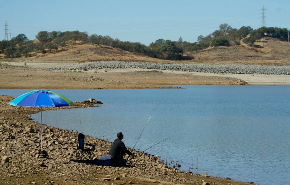 A man places his fishing pole along the shore line of Folsom Lake that would normally be underw ...