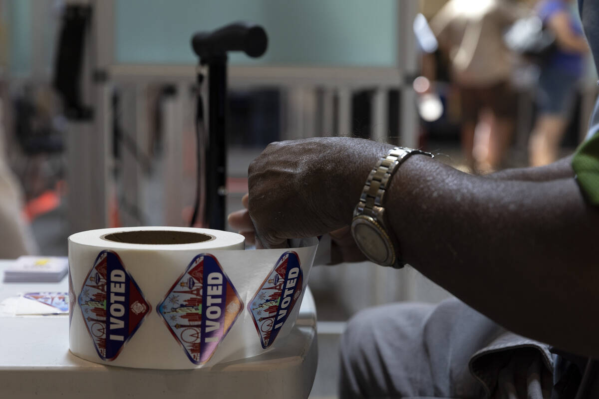 A poll worker prepares stickers for early voters at Galleria at Sunset shopping mall on Saturda ...