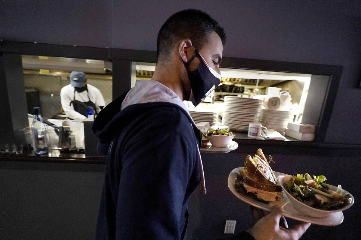 FILE - Bartender Denis Angelov carries plates of food from the kitchen, behind, at Tin Pan Alle ...