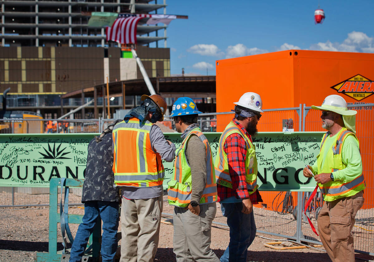 Leaders and construction crews sign the celebratory beam as the final beam is placed at the Dur ...