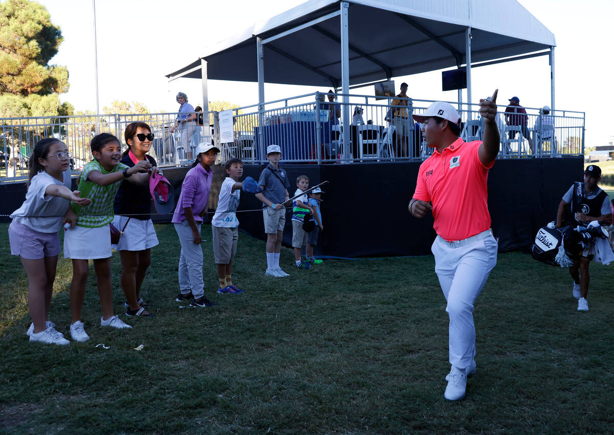 Tom Kim walks off the eighteenth green as fans ask for autographs during the third round of the ...