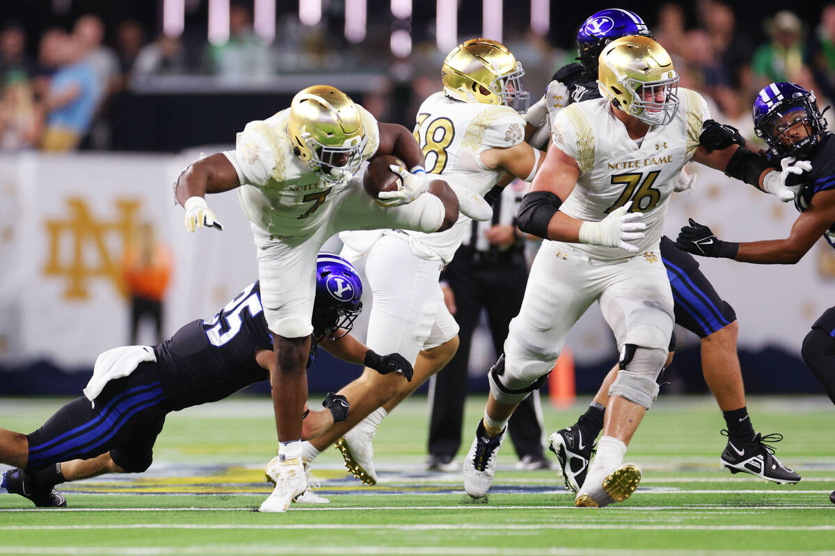 Notre Dame Fighting Irish running back Audric Estime (7) leaps over a tackle attempt by Brigham ...