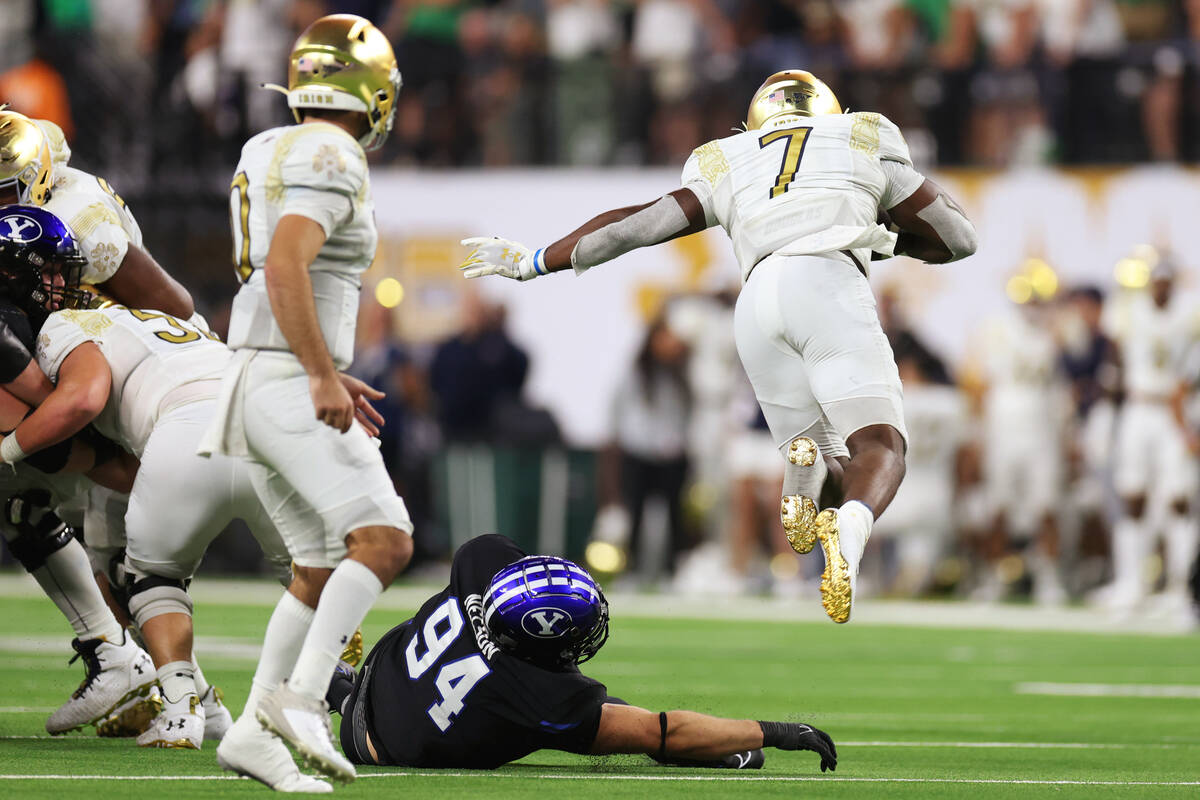 Notre Dame Fighting Irish running back Audric Estime (7) leaps over a tackled attempt from Brig ...