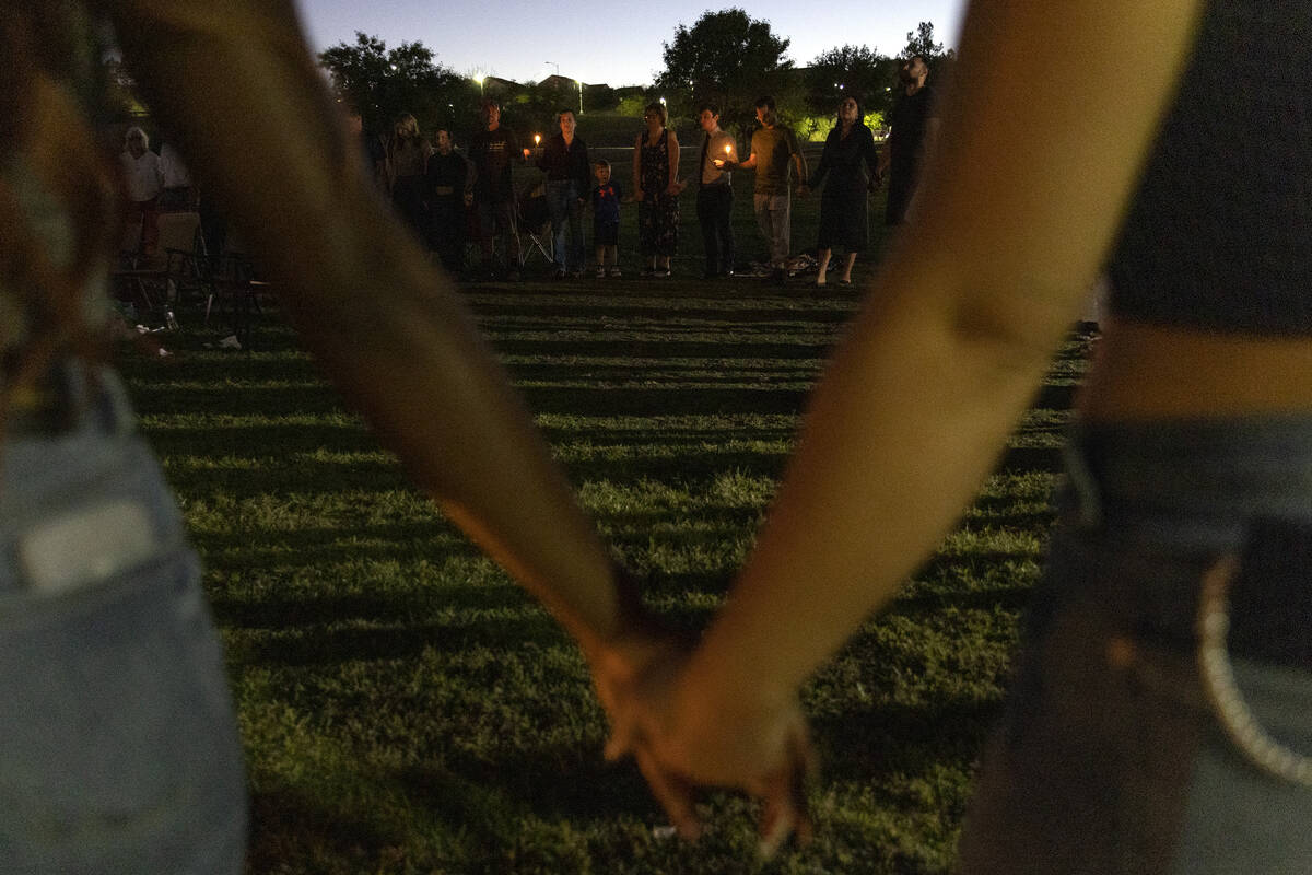 Those who attended a vigil held for Las Vegas Strip stabbing victim Maris DiGiovanni hold hands ...