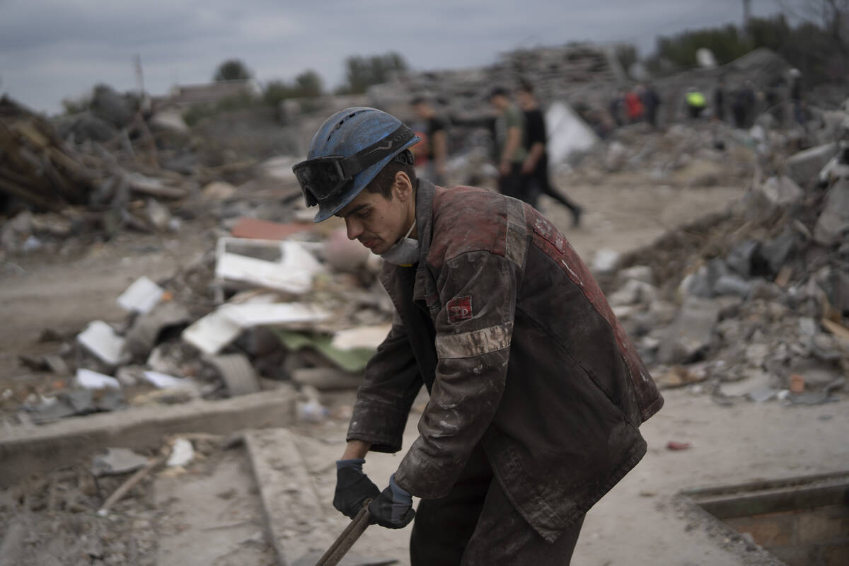 A worker cleans the debris on a site where several houses were destroyed after a Russian attack ...