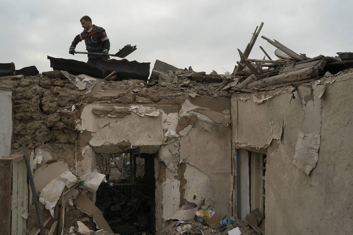 A worker cleans the debris from the roof of a house on a site where several houses were destroy ...