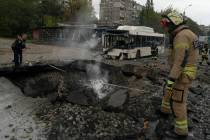 Firefighters and police officers work on a site where an explosion created a crater on the stre ...