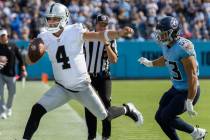 Raiders quarterback Derek Carr (4) tight ropes dow the sideline past Tennessee Titans linebacke ...