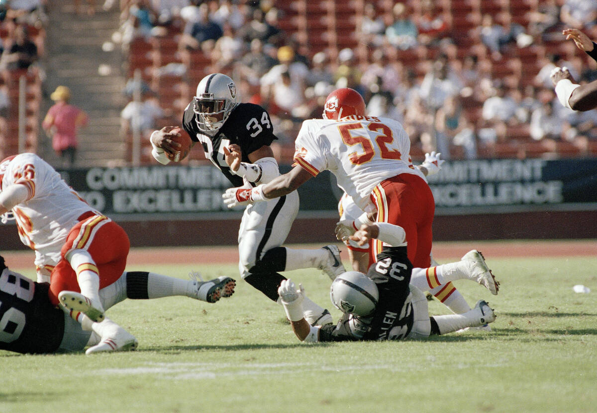Bo Jackson (34) of the Los Angeles Raiders shakes loose from the grip of Jack Snipes (52) of th ...