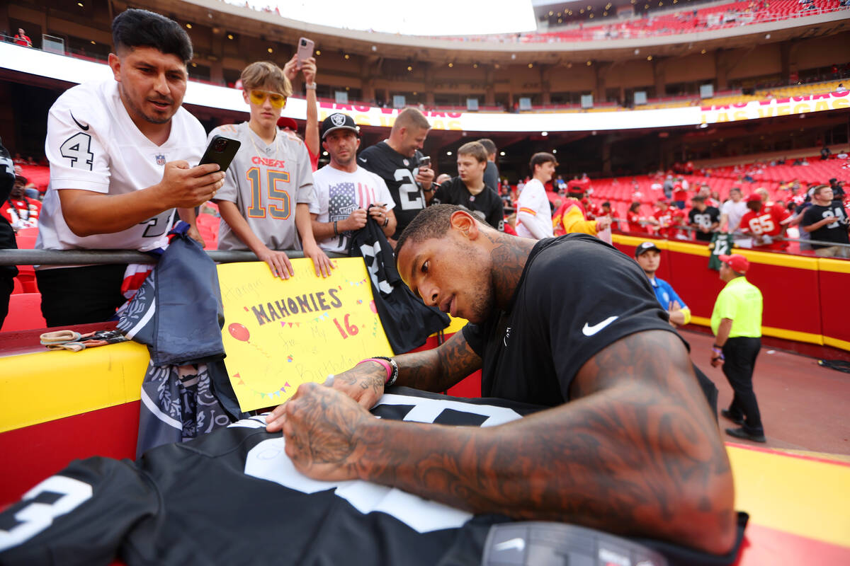 Raiders tight end Darren Waller (83) signs an autograph for a fan before the start of a NFL foo ...