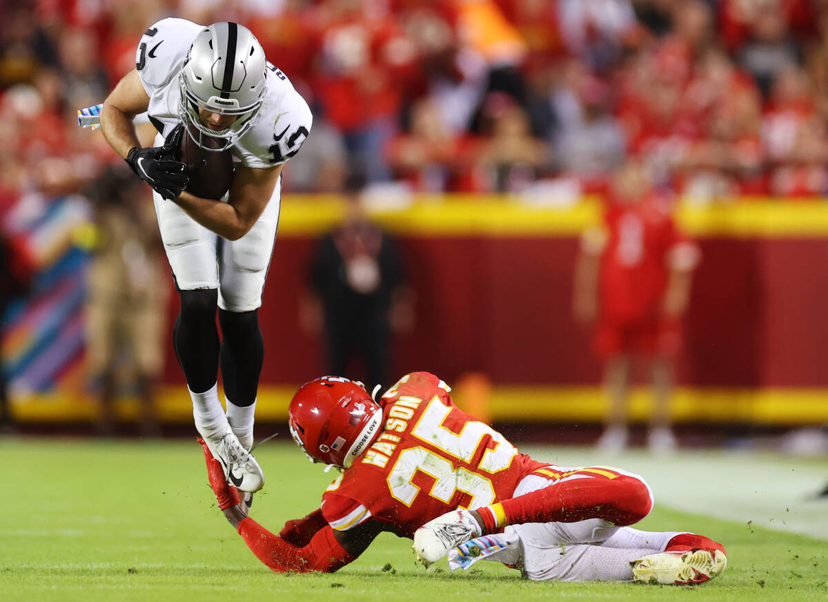 Raiders wide receiver Hunter Renfrow (13) leaps over a tackle attempt by Kansas City Chiefs cor ...