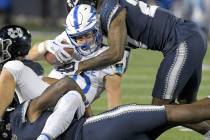 Air Force running back Brad Roberts gets tackled by Utah State defensive end Byron Vaughns, bot ...