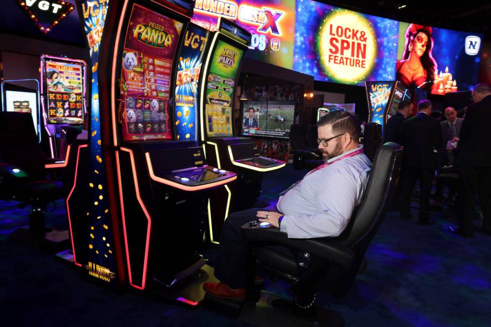 Jason Voltz dari Las Vegas menggunakan tombol di sandaran tangan saat bermain di mesin slot VIP di ...