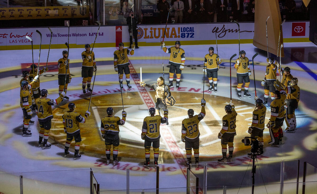 Golden Knights players hold their sticks high after being introduced versus the Chicago Blackha ...