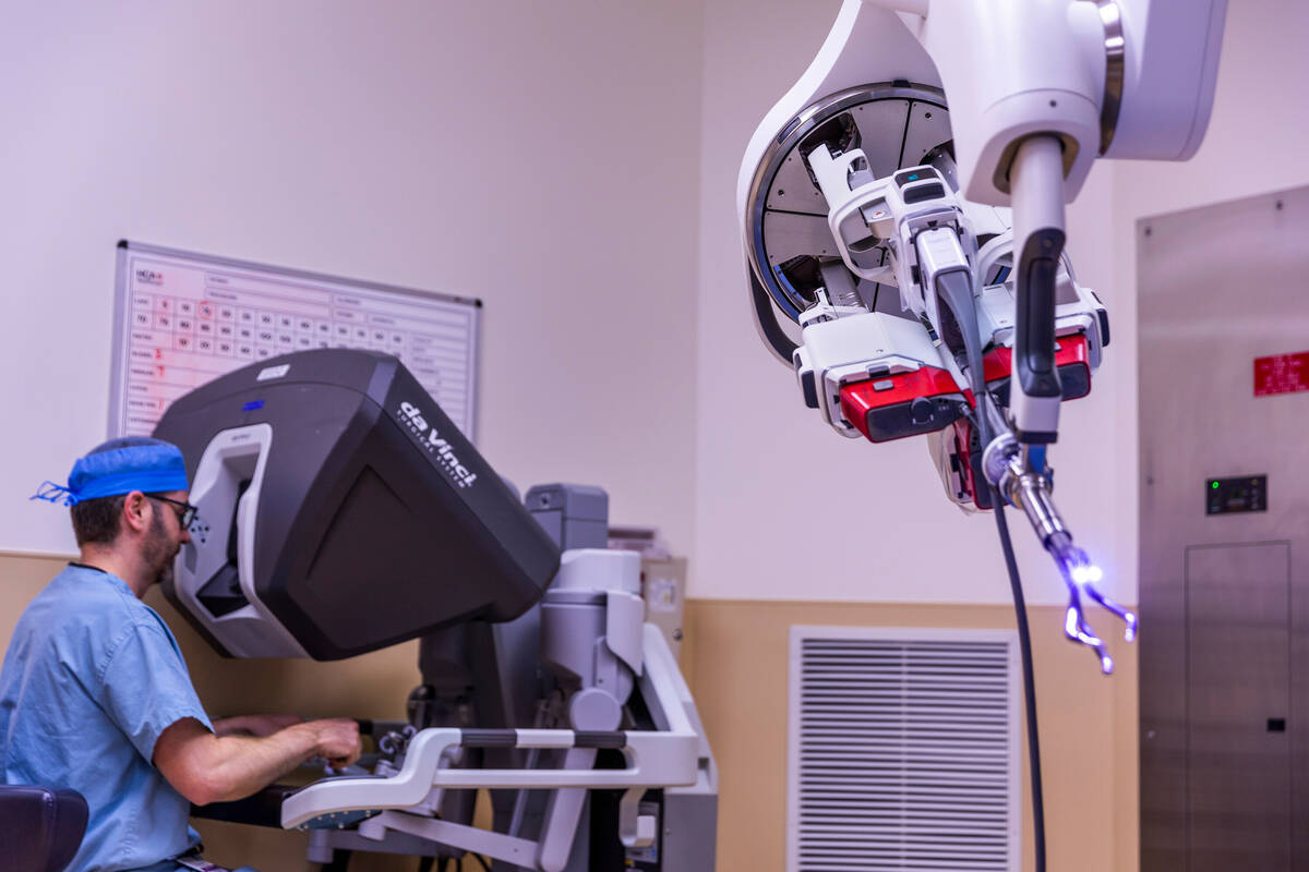 Dr. Garrett Friedman sits at the console, left, of a da Vinci SP surgical robot with patient ca ...