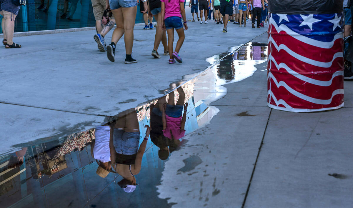 Fans are reflected in water near the pit row during the Alsco Uniforms 302 NASCAR Xfinity Serie ...