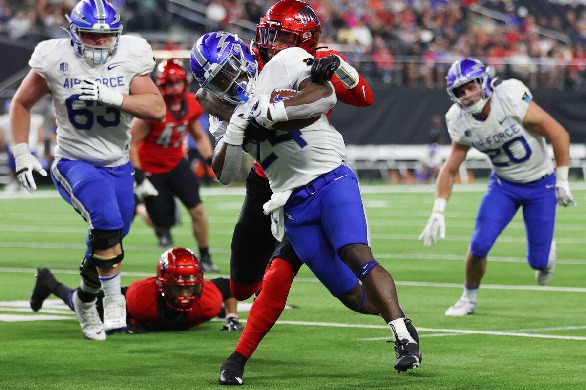 Air Force Falcons running back John Lee Eldridge III (24) gets tackles by UNLV Rebels defensive ...