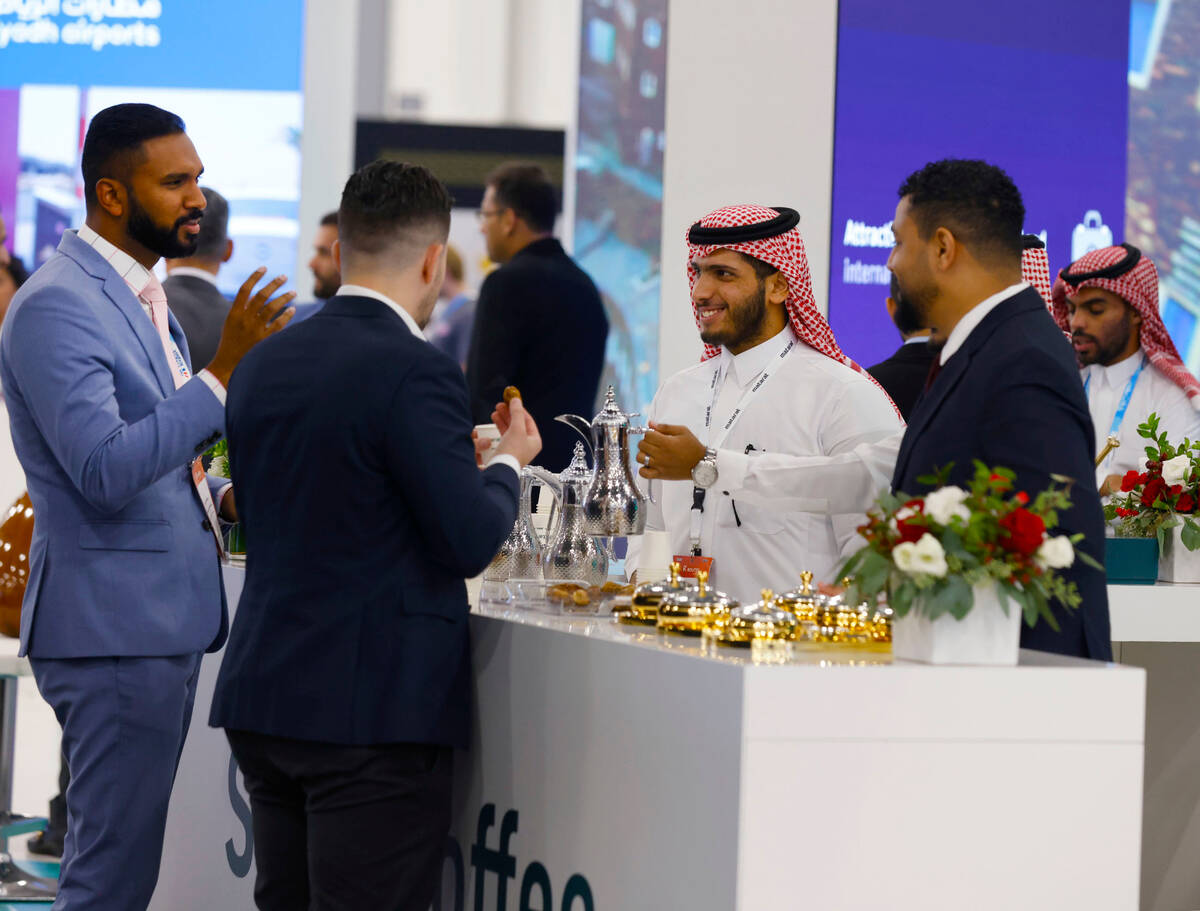 Saad Alathbah, center, a JEDCO representative, serves coffee to forumgoers during the 27th Worl ...