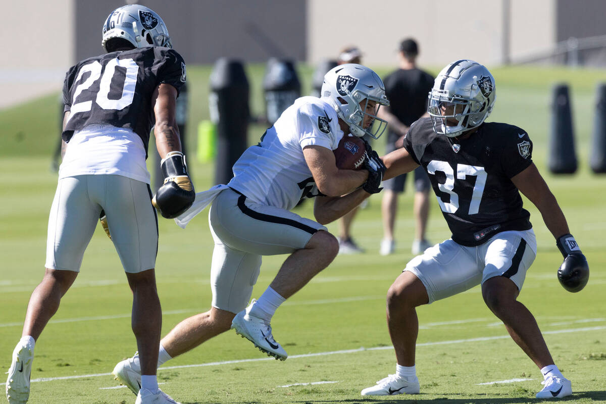 Raiders wide receiver Hunter Renfrow (13) holds on to the football as safety Isaiah Pola-Mao (2 ...