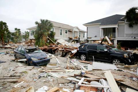 Remnants of damaged homes and flooded vehicles are seen in Fort Myers Beach, Fla., on Thursday, ...