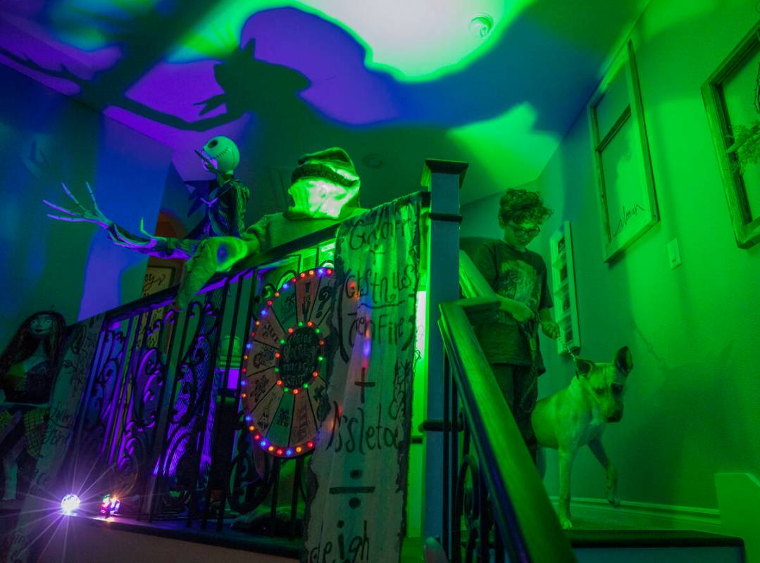 Evan Garcia, 10, walks his dog Jessie down the stairs of their Disney Halloween themed home, in ...