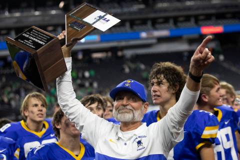 Moapa Valley head coach Brent Lewis holds up his team's Class 3A football state championship tr ...