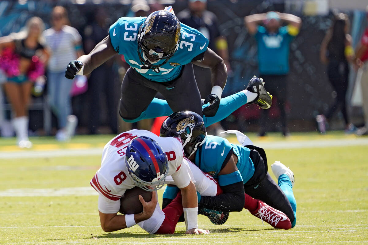 Jacksonville Jaguars linebacker Devin Lloyd (33) flies over New York Giants quarterback Daniel ...