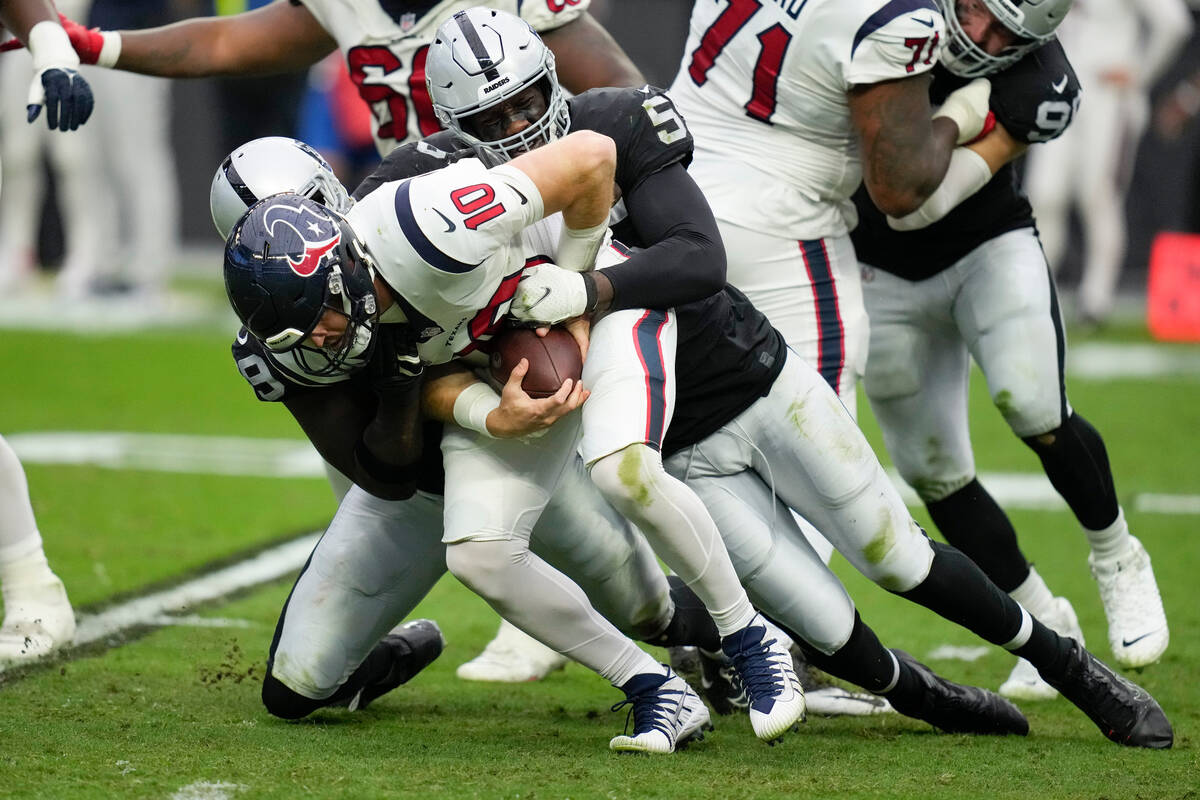 Houston Texans quarterback Davis Mills is brought down for a sack by Las Vegas Raiders defensiv ...