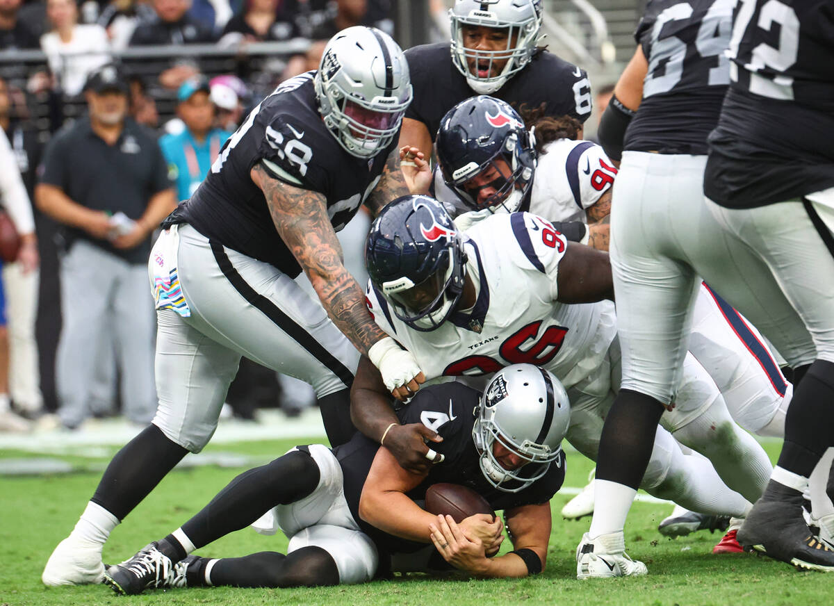 Raiders quarterback Derek Carr (4) recovers a fumble under pressure from Houston Texans during ...