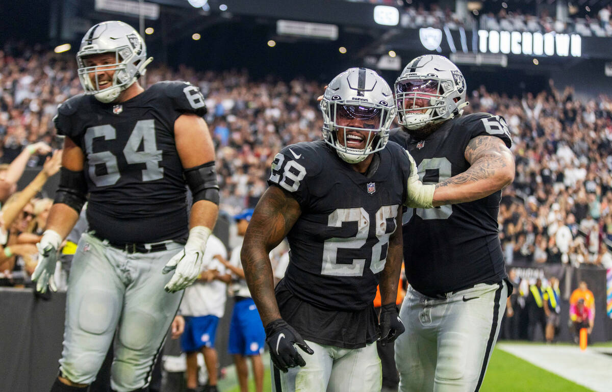 Raiders running back Josh Jacobs (28) celebrates his third touchdown score of the game with gua ...