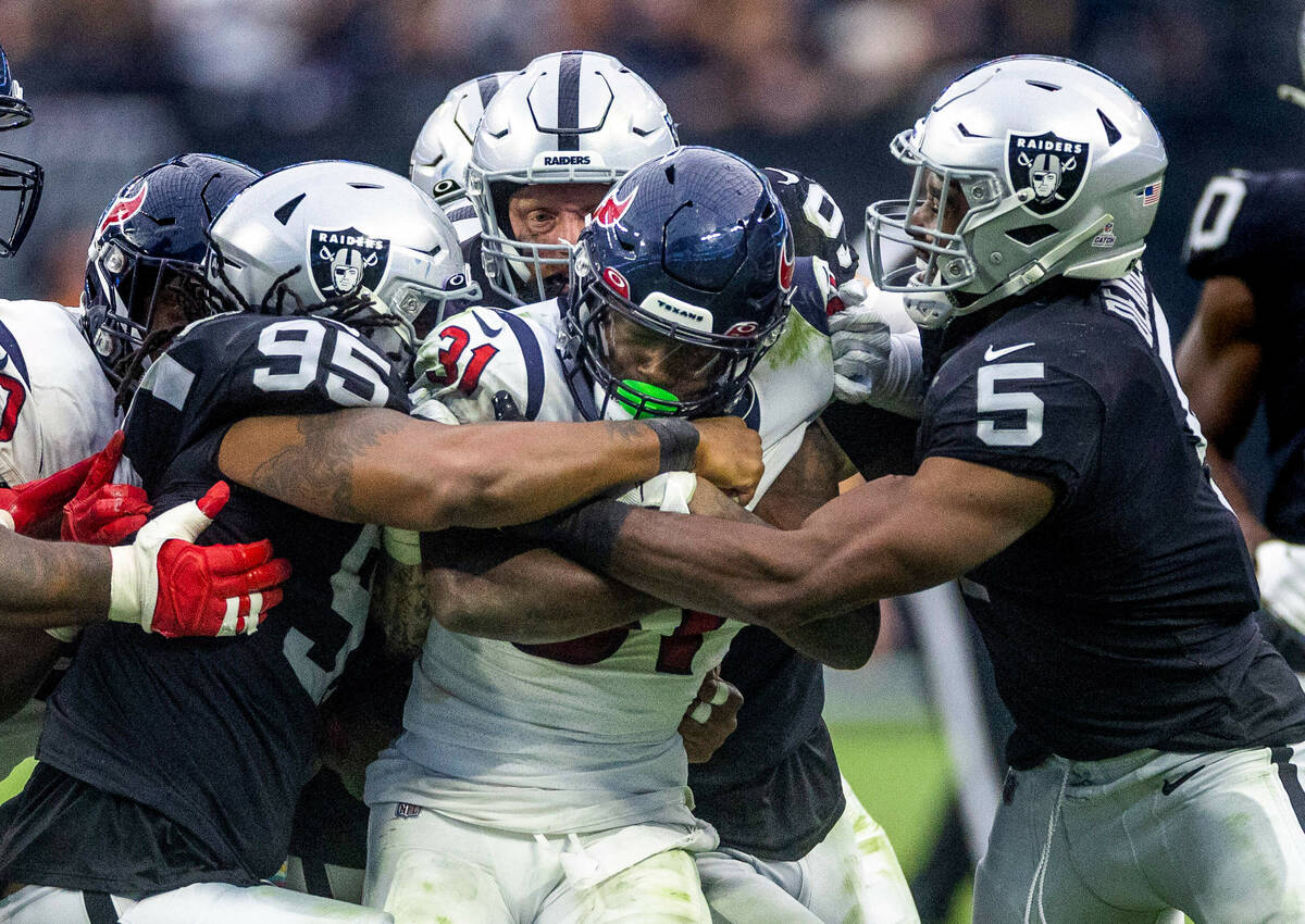 Houston Texans running back Dameon Pierce (31) is gang tackled by Raiders defensive tackle Kend ...
