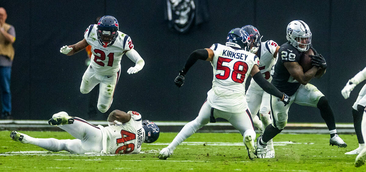 Raiders running back Josh Jacobs (28) avoids a tackle by Houston Texans linebacker Christian Ki ...