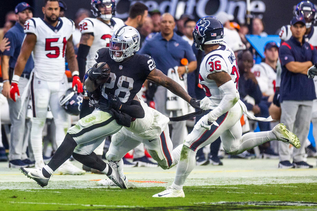 Raiders running back Josh Jacobs (28) drives for more yards on the sidelines as Houston Texans ...