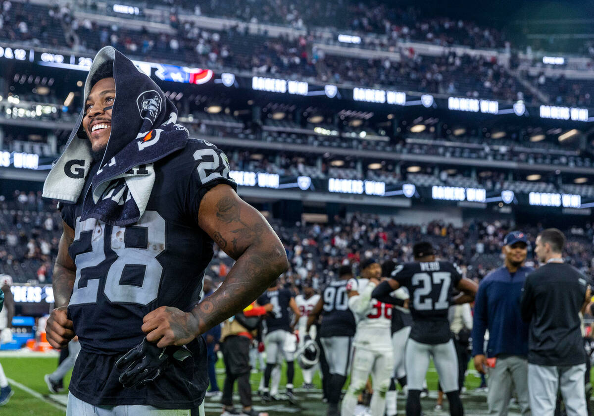 Raiders running back Josh Jacobs (28) is all smiles on the field after the game scoring three t ...