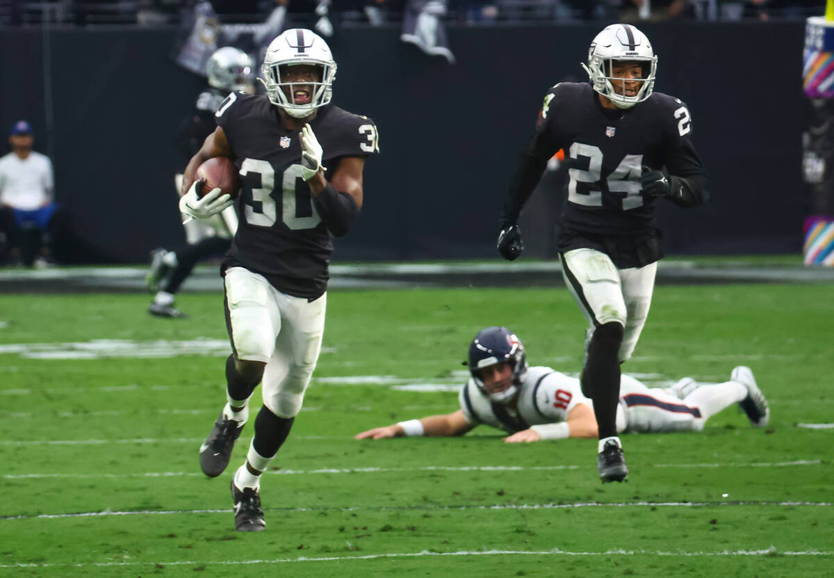 Raiders safety Duron Harmon (30) runs the ball for a touchdown after intercepting it from the H ...
