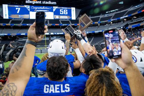 Bishop Gorman players and coaches hoist the trophy together on the field after beating McQueen ...