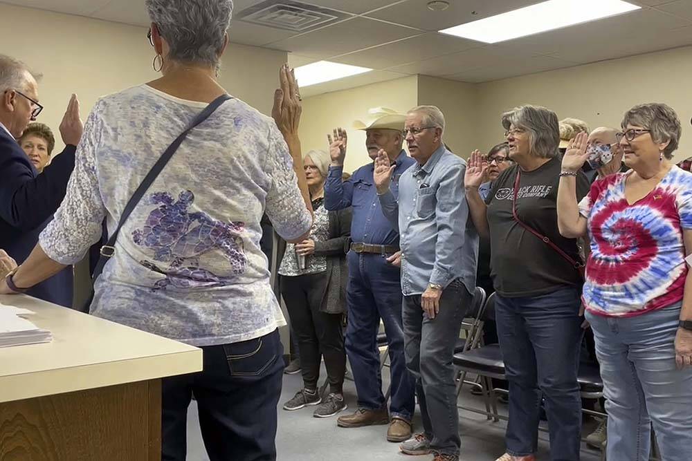 In this image from video, Nye County Clerk Mark Kampf, far left, in suit, swears in a group of ...