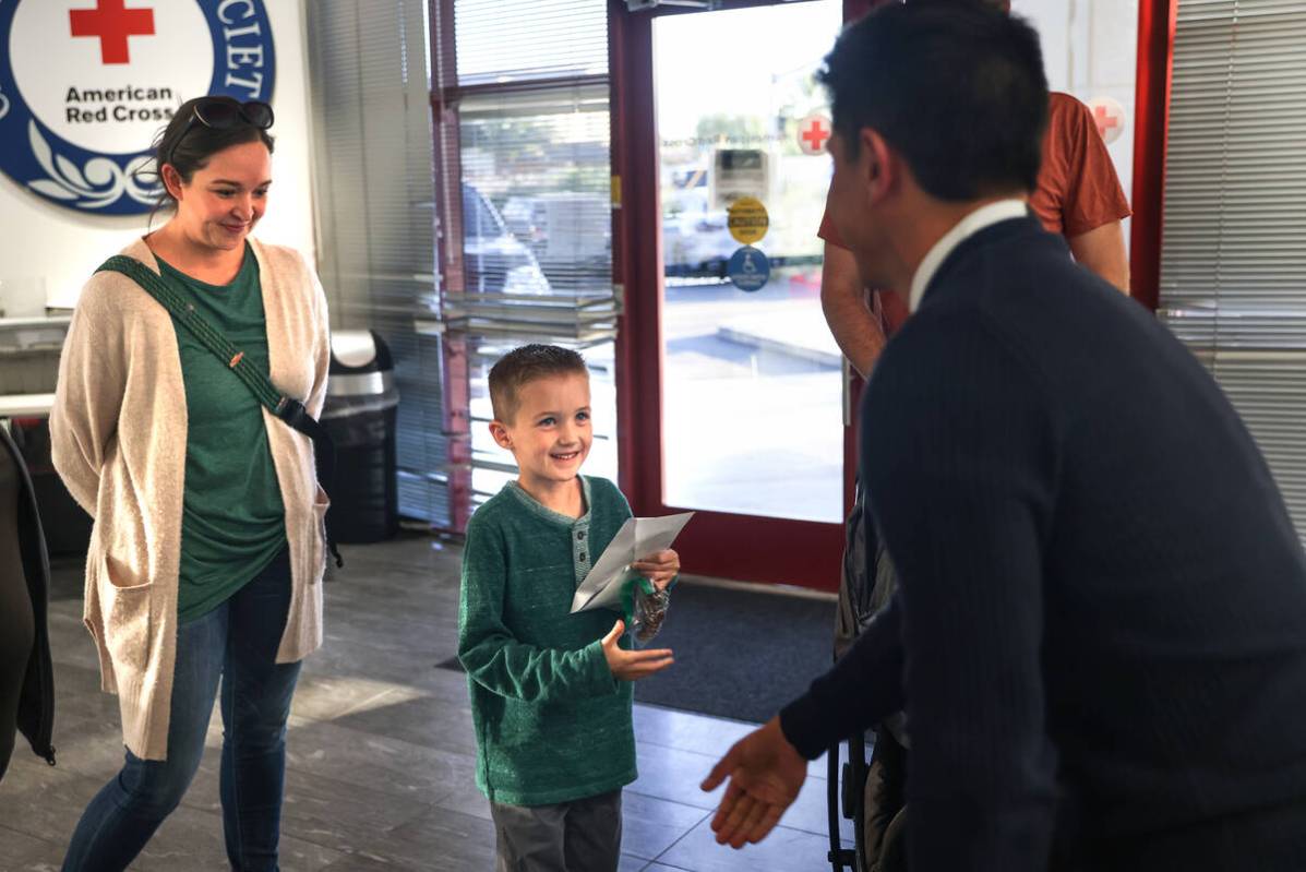 Henry Williams, 6, shakes hands with Chad Kaercher, a Red Cross board member, next to his famil ...