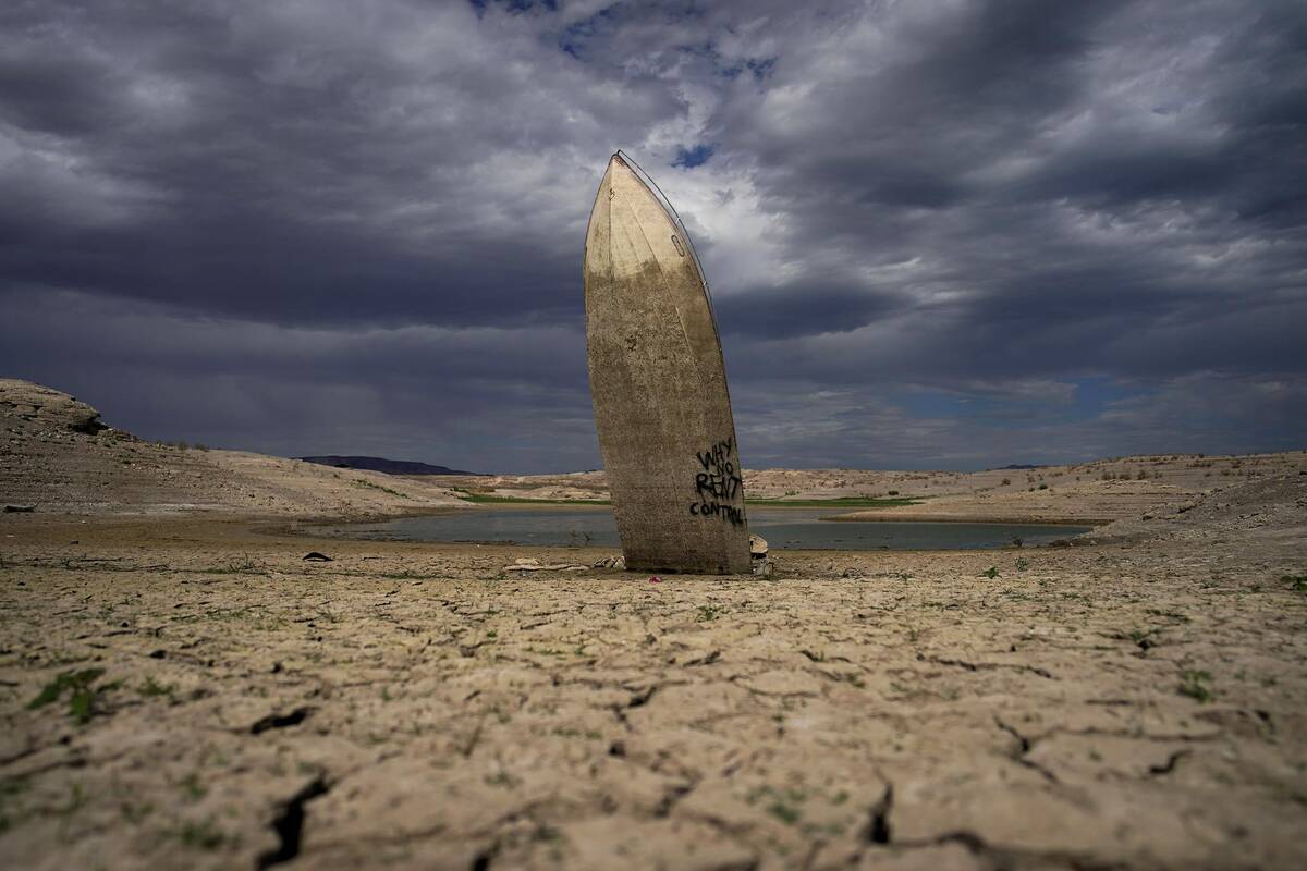 FILE - A formerly sunken boat stands upright into the air with its stern buried in the mud alon ...