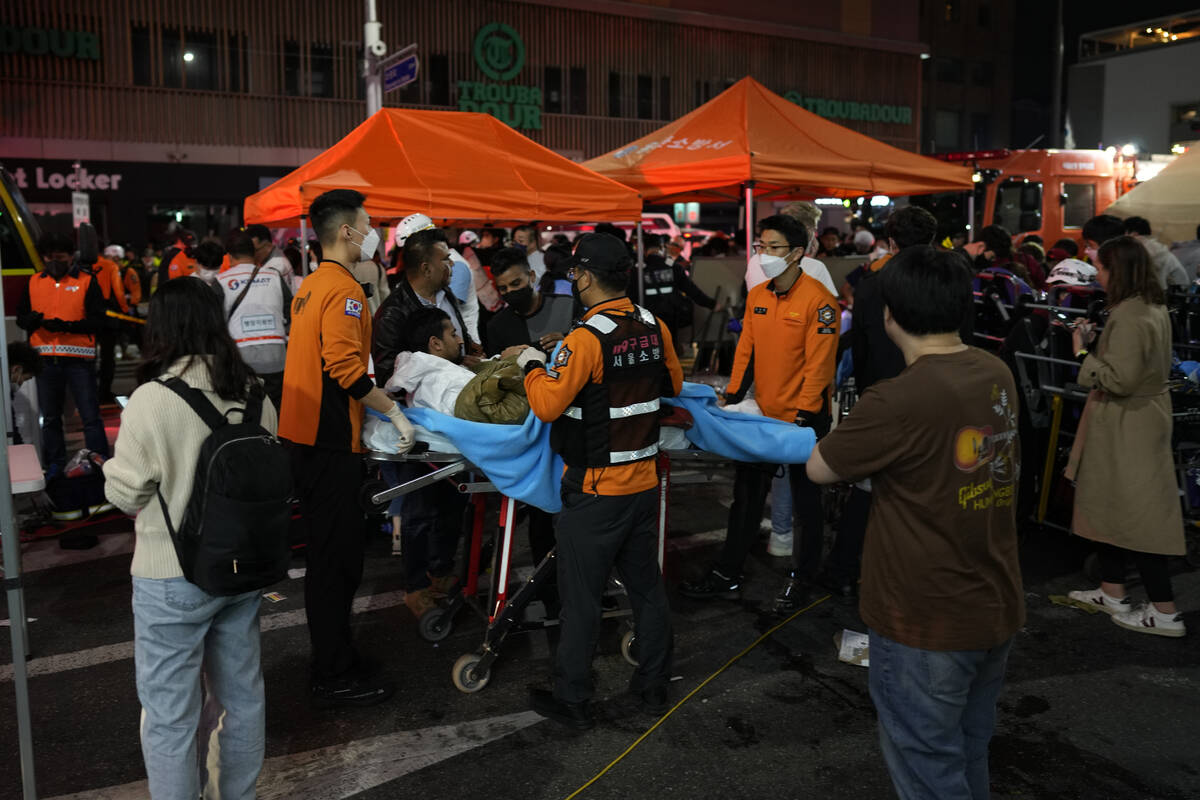 Rescue workers carry injuried people at the street near the scene in Seoul, South Korea, early ...