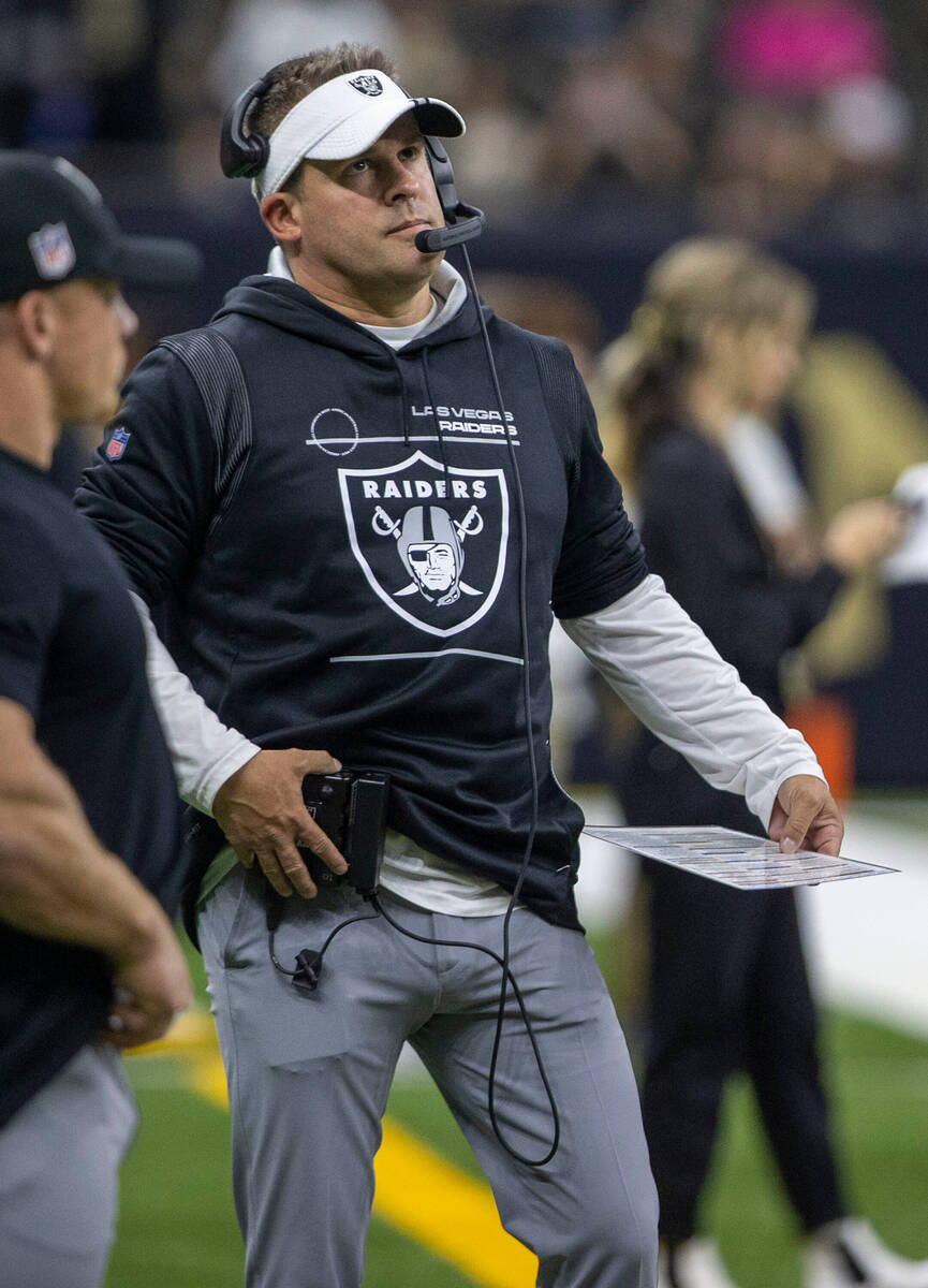 Raiders head coach Josh McDaniels adjusts his headset before an NFL game between the Raiders an ...