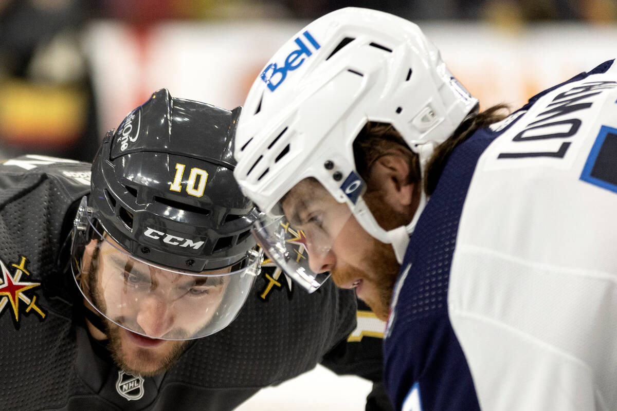 Vegas Golden Knights center Nicolas Roy (10) faces off against Winnipeg Jets center Adam Lowry, ...