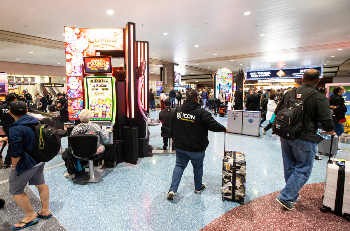 Travelers pass by slot machines in the Terminal 1 baggage claim area at Harry Reid Internationa ...