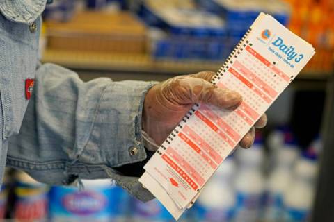 Philip Smith wears gloves as he lines up to purchase lottery tickets for the Monday, Oct. 31, d ...