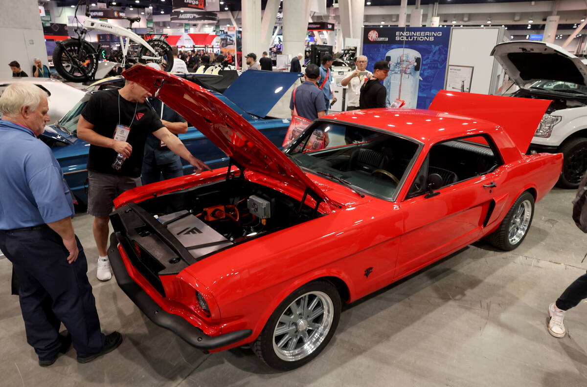 Conventioneers check out a 1965 Ford Mustang converted to an electric vehicle in the AEM EV boo ...