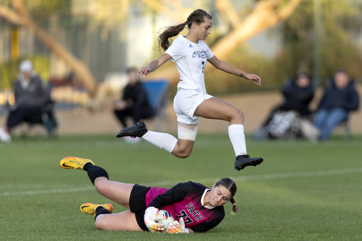 Shadow Ridge’s Brynn Belcher (7) jumps over Faith Lutheran’s Elke Travis (77) whi ...