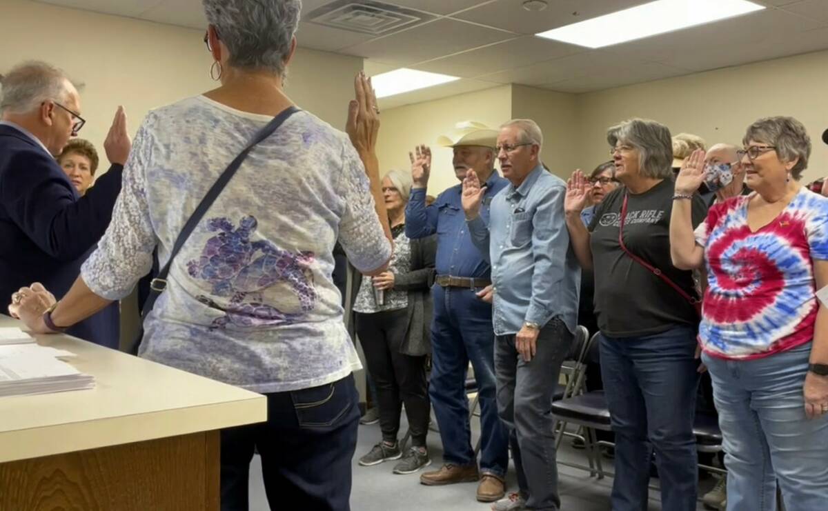 Nye County Clerk Mark Kampf, far left, in suit, swears in a group of residents who will hand co ...